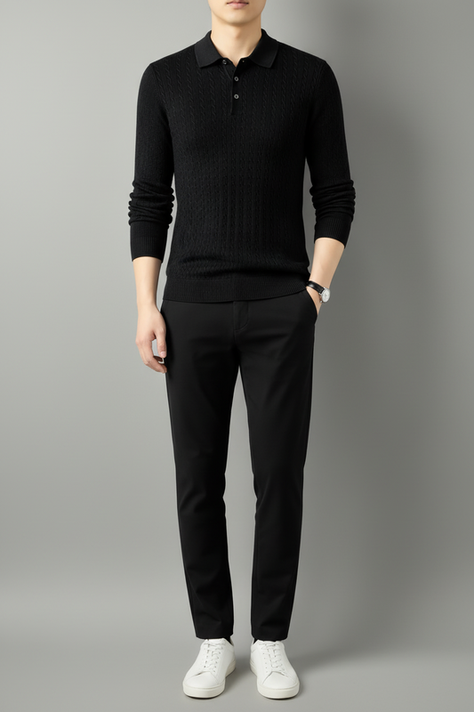 Men’s black cable-knit collared sweater with long sleeves, styled with black trousers on a neutral gray studio background.